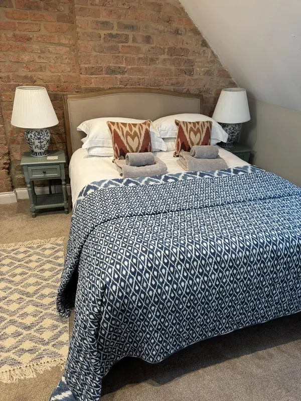 Airbnb guest bedroom with exposed brick wall and patterned bedding, cleaned by True Grit Cleaning Co in Richmond