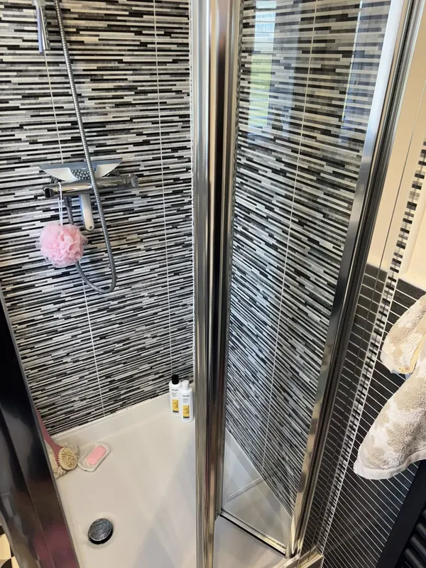 Mosaic-tile shower enclosure with chrome fixtures sparkling clean by True Grit Cleaning Co