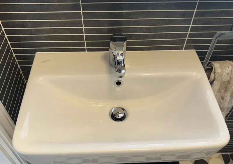 Cream and dark-grey tile bathroom with chrome tap and white basin cleaned by True Grit Cleaning Co in Richmond