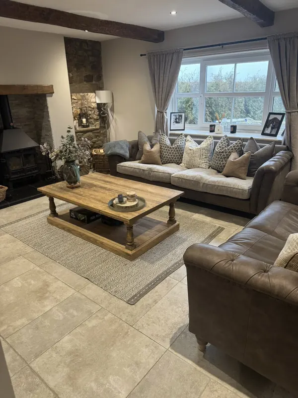 Cosy cottage living room with stone fireplace, exposed beams and chesterfield sofa cleaned by True Grit Cleaning Co in Richmond