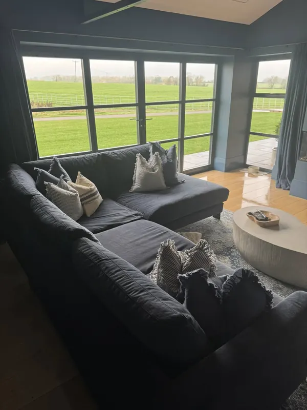 Modern lounge with grey velvet corner sofa and floor-to-ceiling countryside views, professionally cleaned by True Grit Cleaning Co in Darlington
