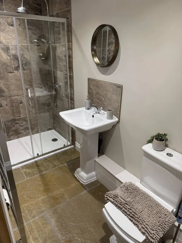 Stone-tile holiday let en-suite bathroom with walk-in shower cleaned by True Grit Cleaning Co