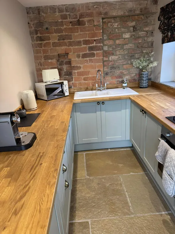 Cottage kitchen with exposed brick wall and oak worktops after deep clean by True Grit Cleaning Co in Richmond, North Yorkshire